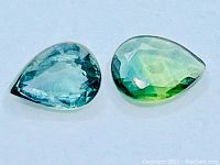 Two pear cut tri-coloured sapphires showing the mix of blue, green, and yellow colors on a white background.