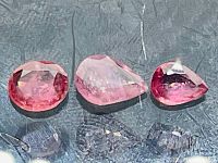 Three natural treated clarity enhanced pink rubies arranged side by side showing color and cut details.