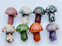 Front view of eight hand-carved natural gemstone mushrooms varied in color and pattern, polished with a glossy finish.