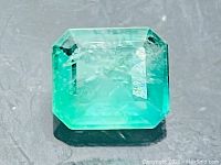 Emerald-cut natural emerald on gray background, top-down view