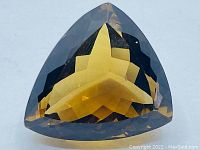 Clear image of the deep Madeira color citrine gemstone, showing trillion cut with sharp precision and sparkling brilliance
