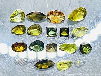 Top down view of mixed cut, various colors of untreated tourmaline gemstones arranged in rows, showing variety in size and shape