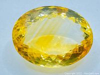Faceted oval cut golden citrine gemstone displaying rich golden-yellow color and clarity.