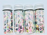 Four glass viles filled with mixed sizes and colors of rough cut Tourmaline crystals, showing the colorful assortment inside each vial.