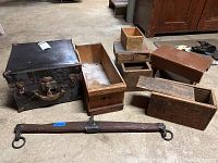 Full view of the lot showing black metal lockbox, three wooden boxes, yoke and stool on concrete floor.