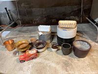 Photo of all items in the lot including crocks, metal pail, metal garden labels, fire engine planter, and other ceramic pots arranged on floor