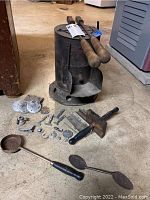The entire lot arranged on floor showing furnace, wood handled metal tools, miniature molds, cast figures, and ladles.