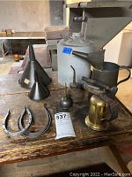 Overview of the lot showing metal oil cans, funnels, horseshoes, and the Craftsman torch on a wooden table