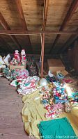 Wide view of assorted Christmas decorations including figurines, boxes of ornaments, and linens laid out on yellow and green fabric.