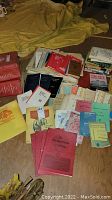 Overview photo of multiple stacks of vintage fire training books and manuals spread on the floor with various colors and conditions.
