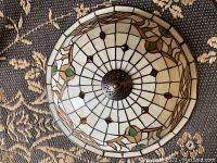 Top view showing the full dome-shaped Tiffany style stained glass shade with floral and geometric design in white, green, amber, and beige colors with a bronze central mount.