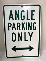 Photo showing one metal parking sign with green 'ANGLE PARKING ONLY' text and left-right arrows, with mounting holes visible.
