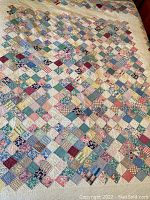 Full view of the vintage patchwork quilt showing the multicolored diamond pattern created with small fabric squares sewn together.