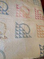 Full view of quilt showing multiple basket block patterns in pastel blue, pink, and floral prints on white background