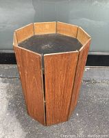 Octagonal vintage teak planter showing top view of the inner low level with black base and teak wood vertical panels on outer sides.