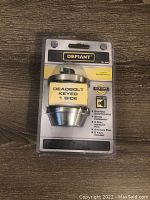 Photo of unopened Defiant deadbolt lock in original package showing front of packaging and hardware inside.