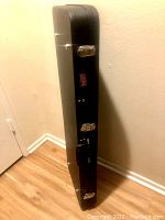 Side view of GATOR hard case standing upright against wall showing black textured finish and silver latches.