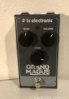 Front view of the tc electronic Grand Magus distortion guitar pedal showing gain, volume, and tone control knobs, red LED indicator, and footswitch.