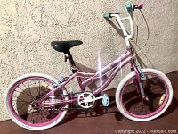 Front side view of pink Huffy kids bike showing frame, handlebars, seat, and front tire.