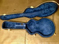 Open view of the guitar case showing plush blue interior lining contoured for electric guitar.