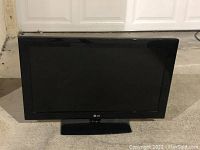 Front view of the black LG 32-inch LCD HDTV turned off on its stand.