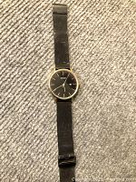 Front of men’s BUREI wristwatch showing black dial, gold-tone case, and black mesh band with some wear.