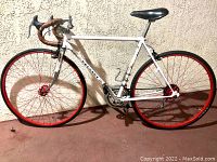 Right-side view showing white steel frame, red wheels, drop bars and black saddle