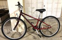 Side view of Schwinn mountain bike with red frame and black tires, showing front and rear wheel and seat