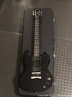 Full view of black Epiphone Special SG electric guitar laid on hard case.