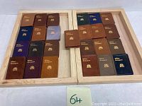 Full overview of all 27 miniature leather-bound William Shakespeare books arranged on wooden trays showing various colors and textures.