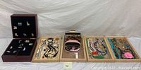 Full lot overview showing wood box with state pins, trays containing costume jewelry and sunglasses.