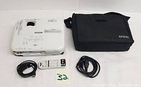 Full lot including Epson projector, remote control, power cable, video cable, and black carrying case.