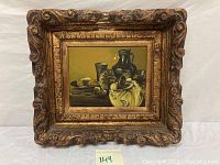 Framed oil painting showing the entire artwork and frame, depicting still life of vessels and food items.