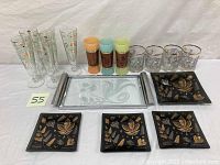 Photo of all glassware and trays including champagne flutes, tumblers, shot glasses, clear serving tray, and black decorative trays with gold/silver motifs.