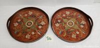Two round lacquered serving trays with floral designs side by side showing general appearance and condition.