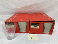 Two original red Lauffer Arabia Tundra boxes with one glass placed outside showing textured surface and box labeling.