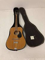 Full view of vintage Mars Horugel acoustic guitar with 11 strings laid open next to its black hard case with yellow trim.