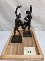 Front view of female and male dancer figurines on wooden tray