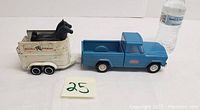 Blue Tonka pickup truck attached to white Tonka Stables trailer containing two black plastic horses with water bottle for size reference.