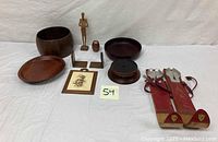 Full lot view showing all wooden items including bowls, carved figure, souvenir skis, framed artwork, and small wooden containers arranged on white background