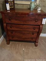 Front view of antique wooden bureau showing four drawers with wooden knobs and wood grain finish.