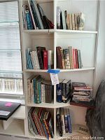 Bookshelf with bird, religious, and non-fiction books loosely arranged, visible worn condition.