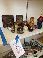 Shelf with assorted painted eggs, Russian dolls, cloisonné boxes, and carved figurines