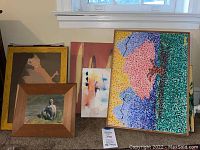 Five art pieces displayed against wall including large pointillist tree landscape, wooden framed nude, red abstract, small abstract, and small gold framed painting