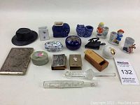 Full lot view showing 14 assorted decor items including ceramic pots, figurines, boxes, thermometers.