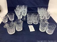 Full set of assorted cut crystal glasses including stemware and tumblers, displayed on a dark cloth background.