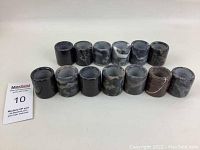 Front view of all 13 ceramic napkin rings arranged in two rows on a white surface showing varied marble patterns.