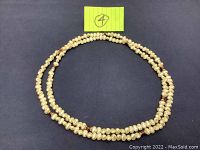 Full view of vintage freshwater pearl necklace laid in a circle on black surface with yellow note showing #4