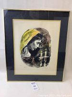 Front view of framed numbered print of woman with candles showing overall condition and framing.