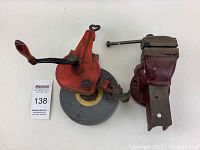 Photo showing the grinding wheel and bench vise side-by-side on a white background from above.